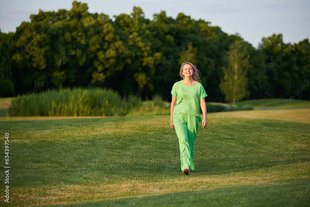 Adult energetic self-confident woman 50 years old, walking on the golf course