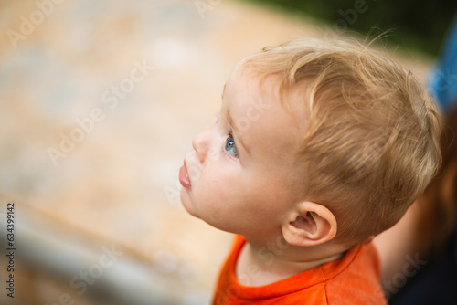 portrait of small boy on background of sandbox in the yard, close-up baby face looking up