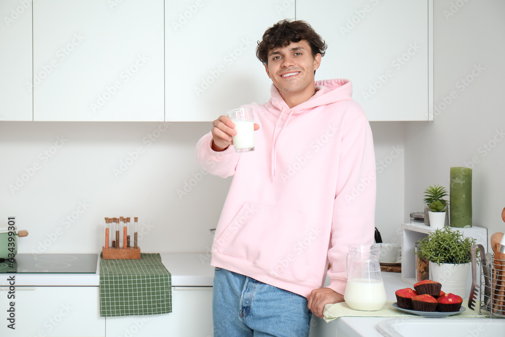 Young man drinking fresh milk in kitchen