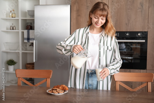 Young woman pouring milk into jug in kitchen