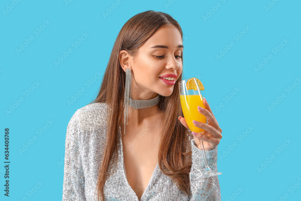 Beautiful young woman with glass of tasty citrus cocktail on blue background Beautiful young woman with glass of tasty citrus cocktail on blue background
