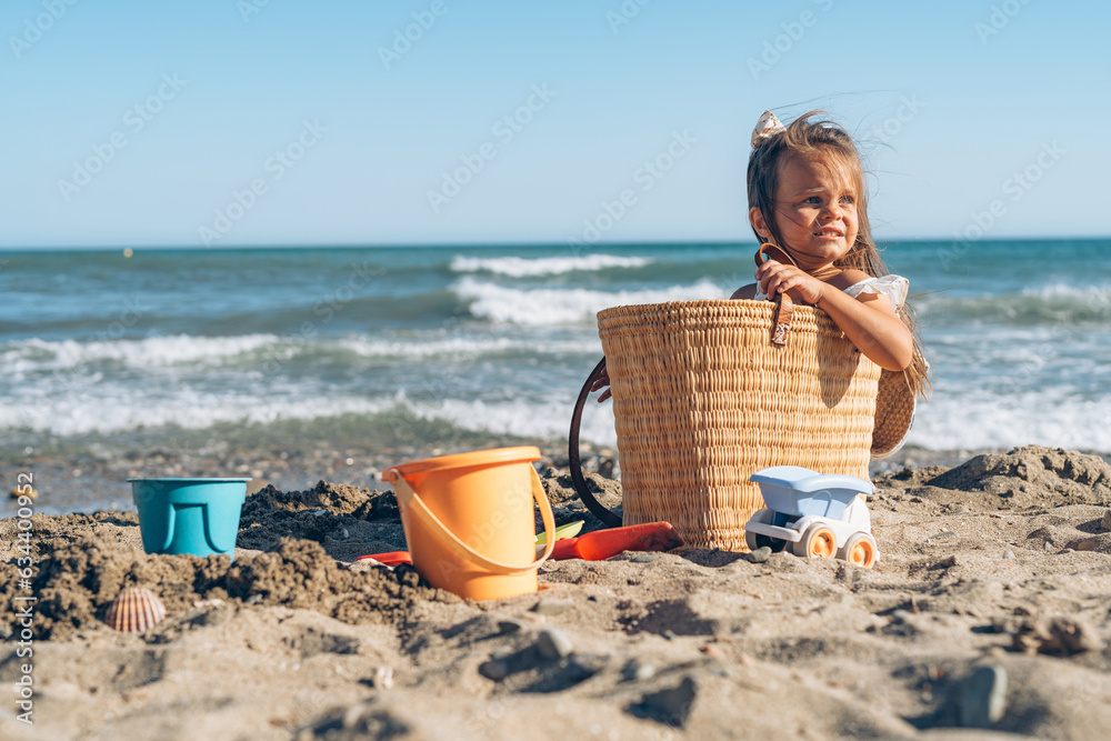 beautiful little brunette girl 4 years old is played in the sand on the seashore in a white dress beautiful little brunette girl 4 years old is played in the sand on the seashore in a white dress