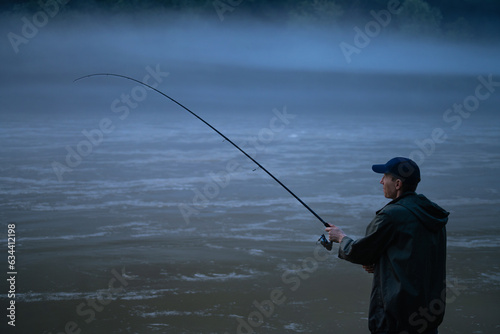 Man fishing on the mountain river at evening