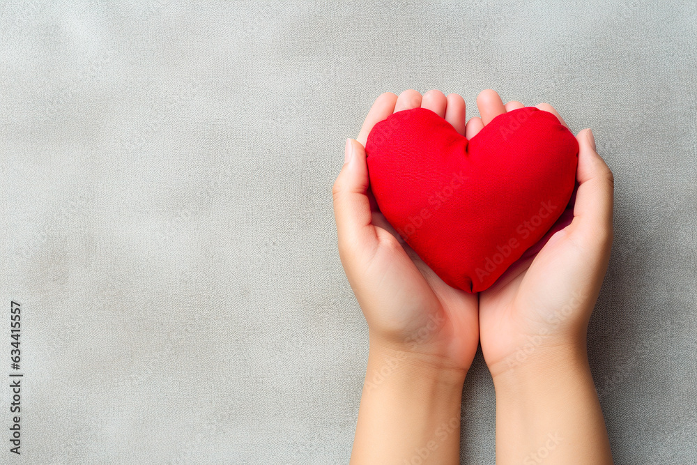 Red heart in woman hands on gray background. Copy space for text. Red heart in woman hands on gray background. Copy space for text.