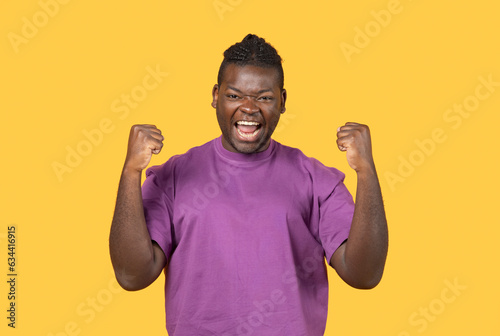 Emotional Black Man Shaking Fists Celebrating Big Luck In Studio