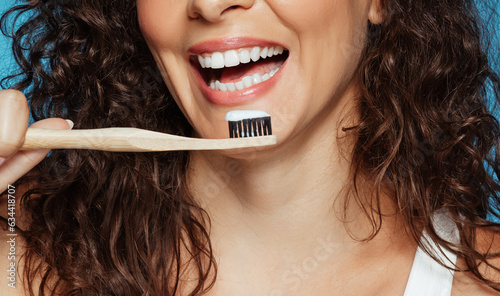 Laughing young european curly woman brushing teeth with toothpaste and toothbrush
