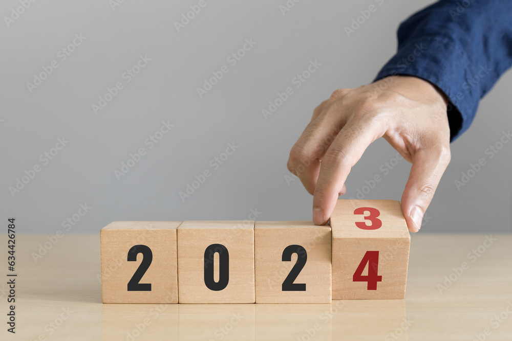 Naklejka premium Hand flip wooden cube with the number 2023 to 2024. Start concept. Happy new year 2024