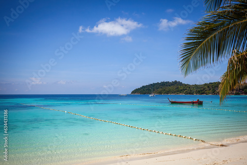 Fototapeta Naklejka Na Ścianę i Meble -  A picturesque tropical beach with crystal-clear turquoise water and a traditional Thai boat. Experience the beauty of nature and the serenity of a secluded paradise.