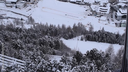 View of snowy Obergurgl Austrian ski resort and ski slopes from above. Aerial view of a snowy village and slopes for winter sports, shot from an ascending ski lift photo