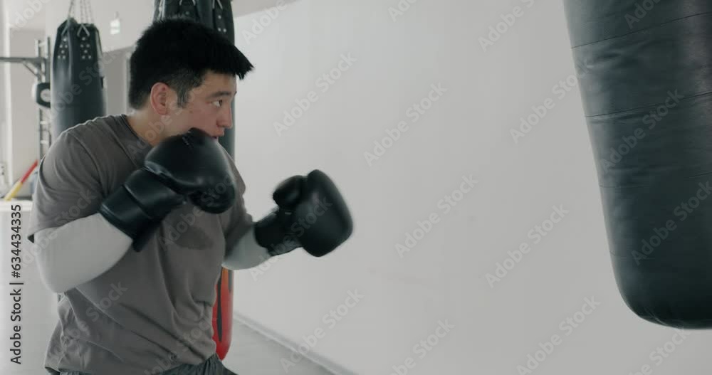 Slow motion of Asian sportsman hitting punching bag preparing for competition in modern sports center. Martial arts and people concept. Slow motion of Asian sportsman hitting punching bag preparing for competition in modern sports center. Martial arts and people concept.