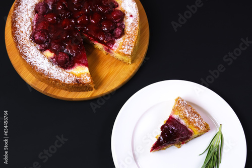 Sliced portion of raspberry pie in a white plate on a dark table. Close-up 