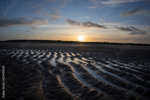 Der Sonnenuntergang am Hollandischen Strand auf dem Sand spiegelt sich die Sonne im Wasser photo