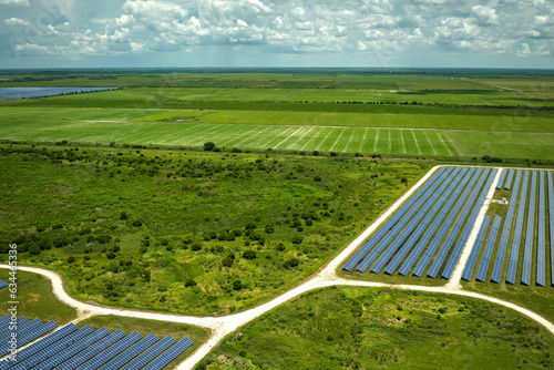 Aerial view of sustainable electrical power plant between agricultural farmlands with photovoltaic panels for producing clean electric energy. Concept of renewable electricity with zero emission