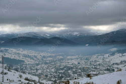 Winter landscape with small village houses between snow covered forest in cold mountains