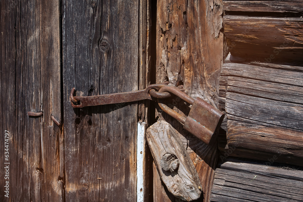 The old iron lock on the old wooden door of the house. The old iron lock on the old wooden door of the house.