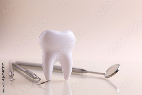 Dentistry concept. Model of a tooth and dental instruments on a colored background with space for text. 