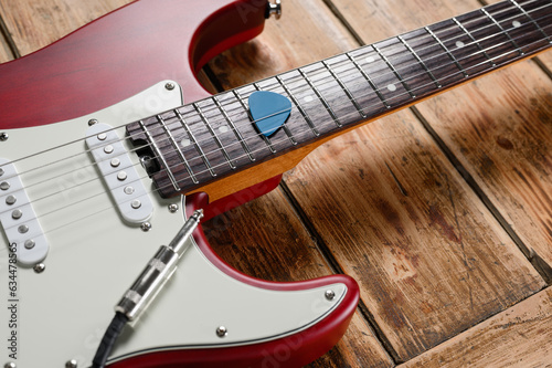 Close-up of an electric guitar and a plectrum on a wooden background. Musical instrument for study or work. Selective focus on mediator