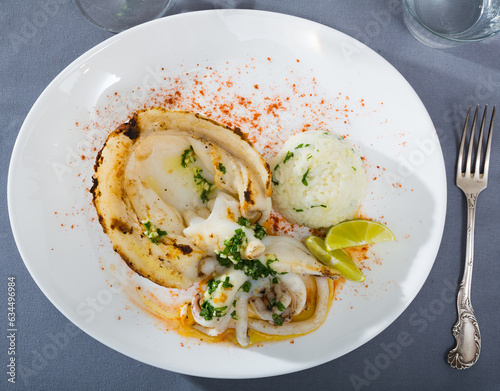 Dish of Mediterranean cuisine – baked in oven cuttlefish, rice, lemon and parsley photo