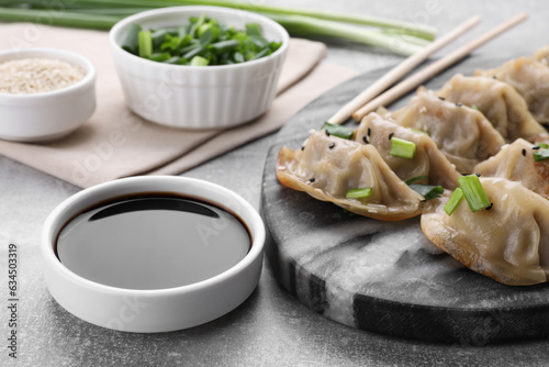 Delicious gyoza (asian dumplings) with green onions and soy sauce on light gray table, closeup