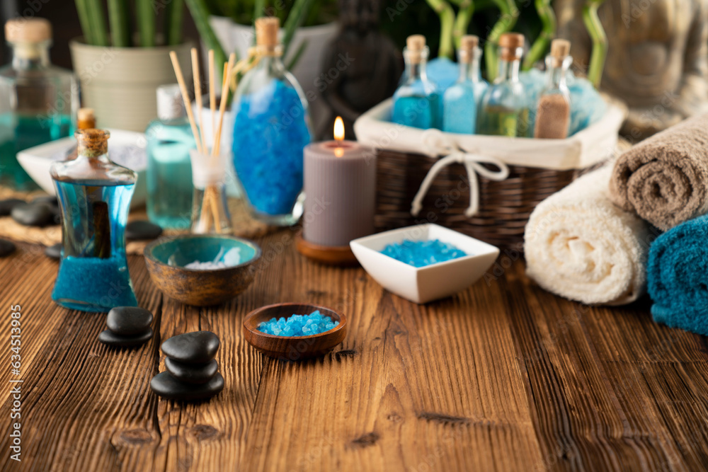 Spa and wellness concept. Bottles with bath and spa cosmetics, rolled up towels, bath salts and care products on wooden rustic paneling.