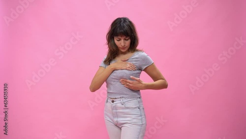 Woman doing a Breast Self-Exam checking up breast changes over pink background.