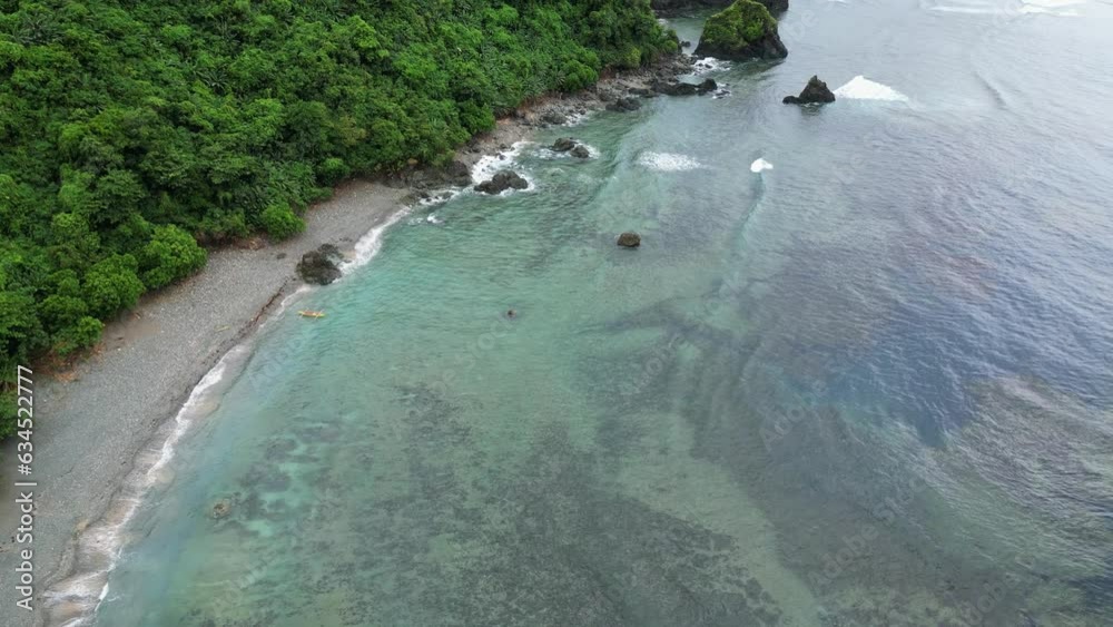 Small yellow fisher boat stranded at exotic beach with rainforest jungle, aerial