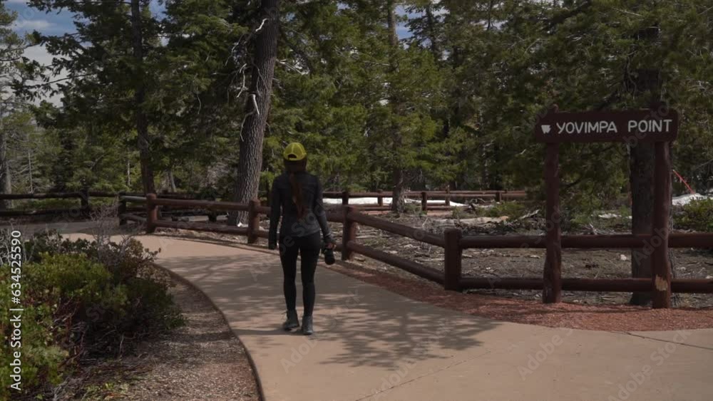 Female Photographer With Camera Walking on Path to Yovimpa Point Cliff and Lookout in Bryce Canyon National Park, Utah USA Female Photographer With Camera Walking on Path to Yovimpa Point Cliff and Lookout in Bryce Canyon National Park, Utah USA