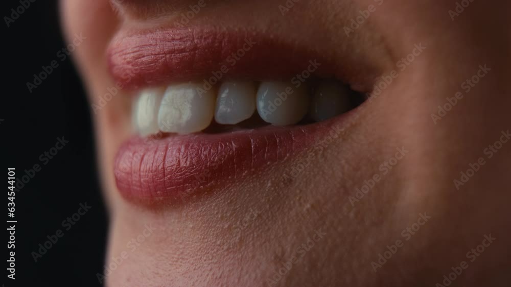 Macro studio shot of woman smiling with close up on lips and teeth shot against black background - shot in slow motion Macro studio shot of woman smiling with close up on lips and teeth shot against black background - shot in slow motion