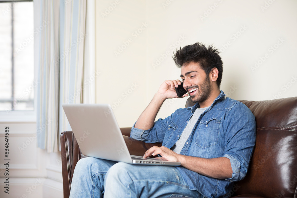 Indian Man using a laptop and phone at home. Indian Man using a laptop and phone at home.