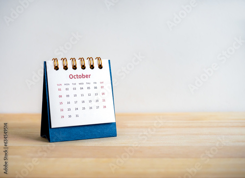 An October 2023 calendar desk for the organizer to plan and reminder isolated on wood table and white background with copy space, minimal style. Blue small table calendar with page of the 10th month. photo