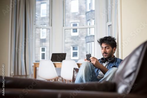 Indian Man using his phone at home.