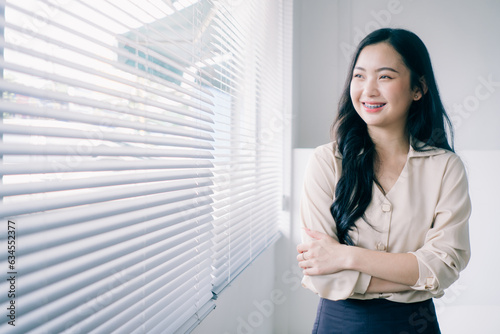 Portrait of young asian woman smiling with arms crossed. Modern business asian woman. Successful businesswoman standing in office with copy space.