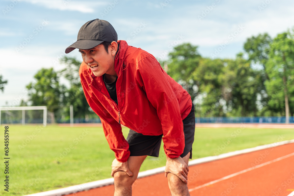 Asian runner man tired during jogging in the running track. Young asian male intense training workout challenge breathing exhausted. Exercise in the morning. Healthy and active lifestyle concept.