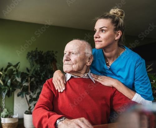 Nurse with thoughtful senior man sitting at home photo