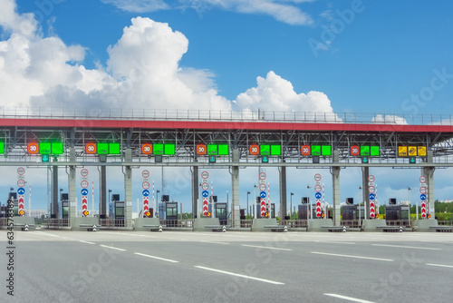 View gate for cars at the entrance to the toll road, limited by the barrier. Cashless payment transponder, speed limit signs. photo