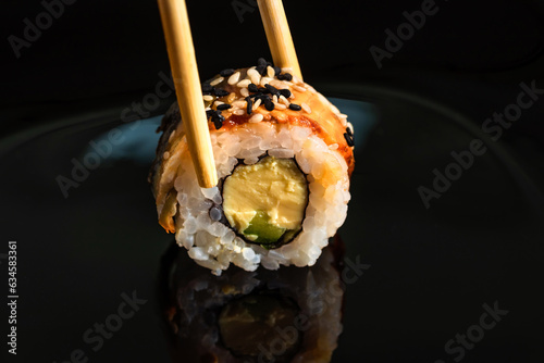Close-up of sushi roll on black background.