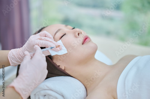 아시아 한국의 젊은 한국여성 모델이 전문병원에 치료실에서 전문의사가 주사기로 얼굴에 성형,노화방지,주름개선 또는 리프팅 시술을 받고 있다. 