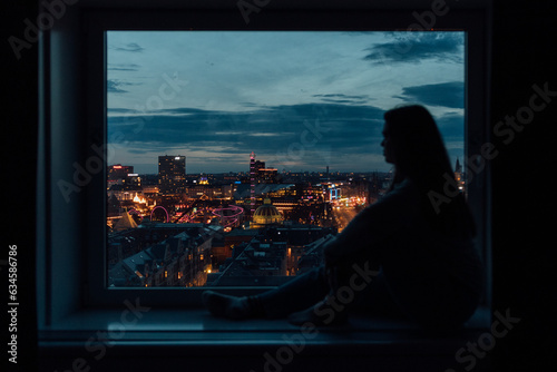 Young woman at window with city in background