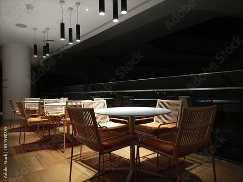 Modern interior design in a building room with Low light photography at night. Tables and chairs under the light with dark background.