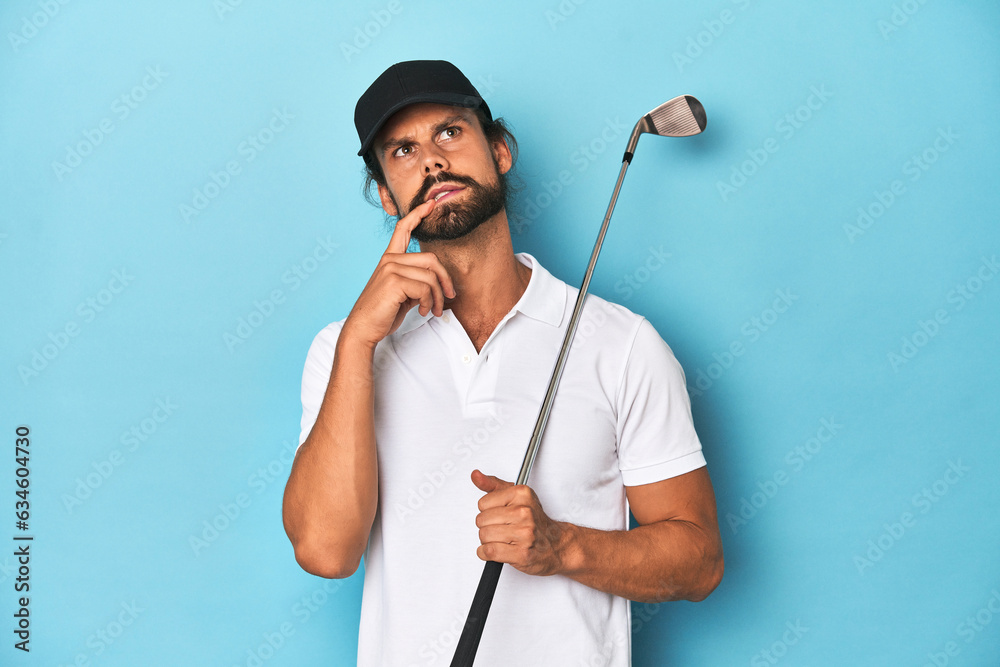 Long-haired golfer with club and hat relaxed thinking about something looking at a copy space. Long-haired golfer with club and hat relaxed thinking about something looking at a copy space.
