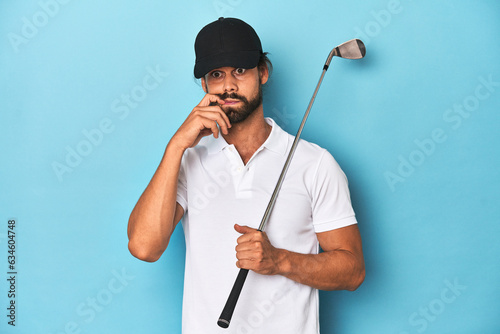 Long-haired golfer with club and hat biting fingernails, nervous and very anxious.