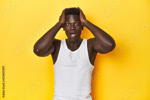 Stylish young African man on vibrant yellow studio background, screaming, very excited, passionate, satisfied with something.