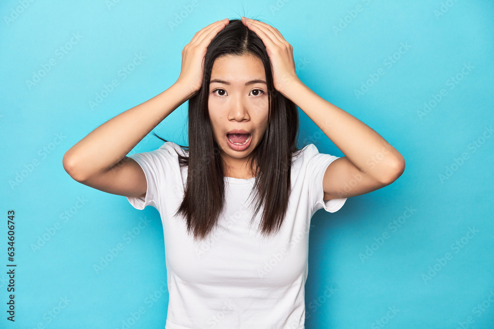 Young Asian woman in white t-shirt, studio shot, screaming, very excited, passionate, satisfied with something.