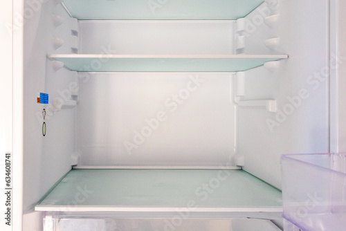 A refrigerator with empty shelves. The concept of lack of food, hunger, poverty