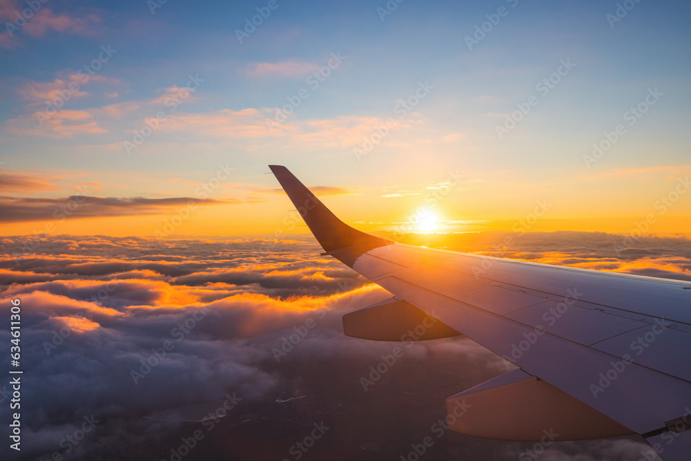 Airplane flight in sunset sky over ocean water and wing of plane. View from the window of the Aircraft. Traveling in air.