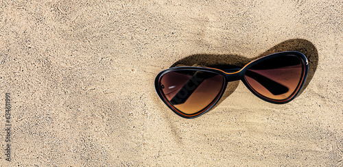 immagine primo piano di eleganti occhiali da sole su una superficie di sabbia, vista da sopra