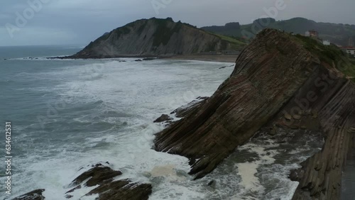 Ocean waves crash on angled cliffs flysch rocks at itzurun beach spain photo
