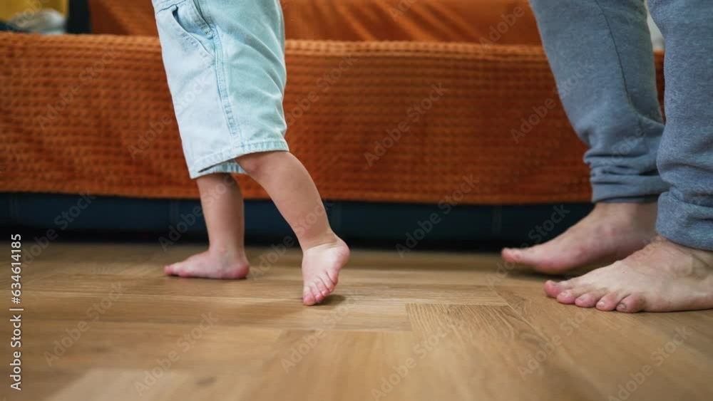 Baby first steps.Toddler at home takes funny first steps.Dad teaches child to walk, legs close-up.Toddler feet on laminate floor.Father's day child education.Kid dream study at home.walk baby learning Baby first steps.Toddler at home takes funny first steps.Dad teaches child to walk, legs close-up.Toddler feet on laminate floor.Father's day child education.Kid dream study at home.walk baby learning