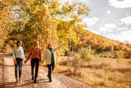 Multiracial female people with different bodies and hairs walking in the fall parks together. Friends wearing warm fashion clothes, knitted sweaters.