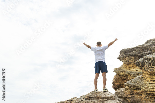 A man on a rock is engaged in energy practices, hands up